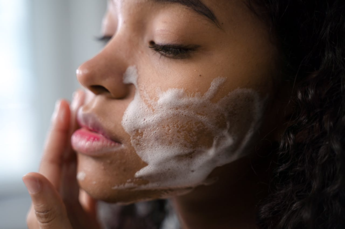 Profile of a young black woman with cleansing foam on her cheek.