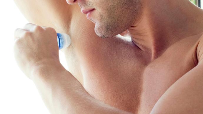 Homme qui se met du déodorant roll-on