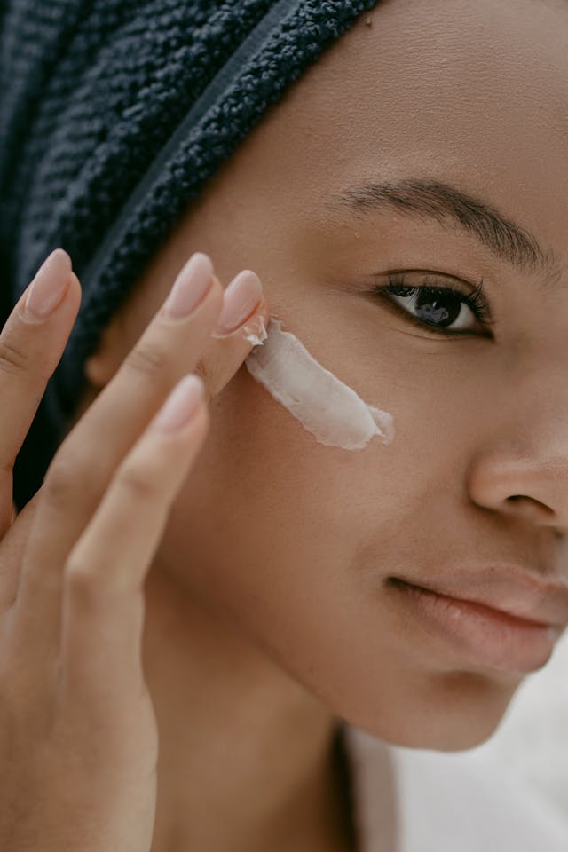 Jeune femme noire qui met de la crème sur sa joue