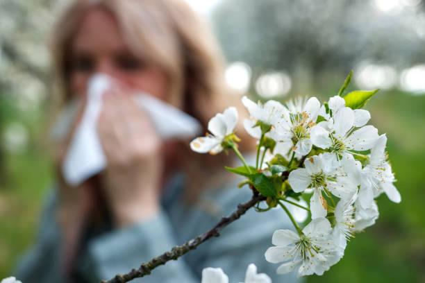 Jeune femme floue qui tient un mouchoir avec des fleurs blanches au premier plan