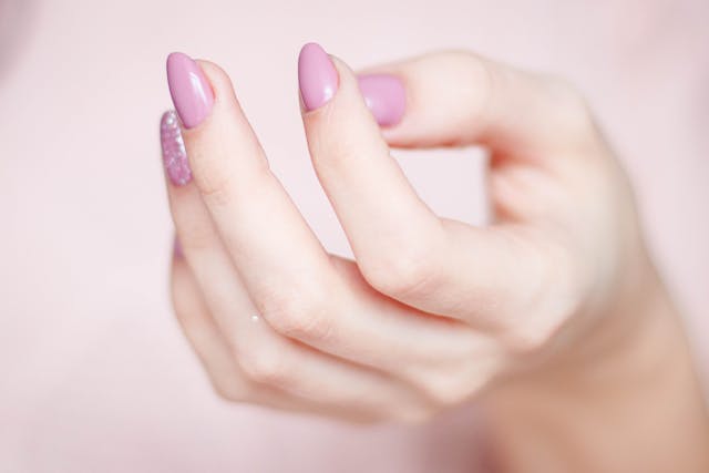 Women's nails with pink nail polish, one glittery