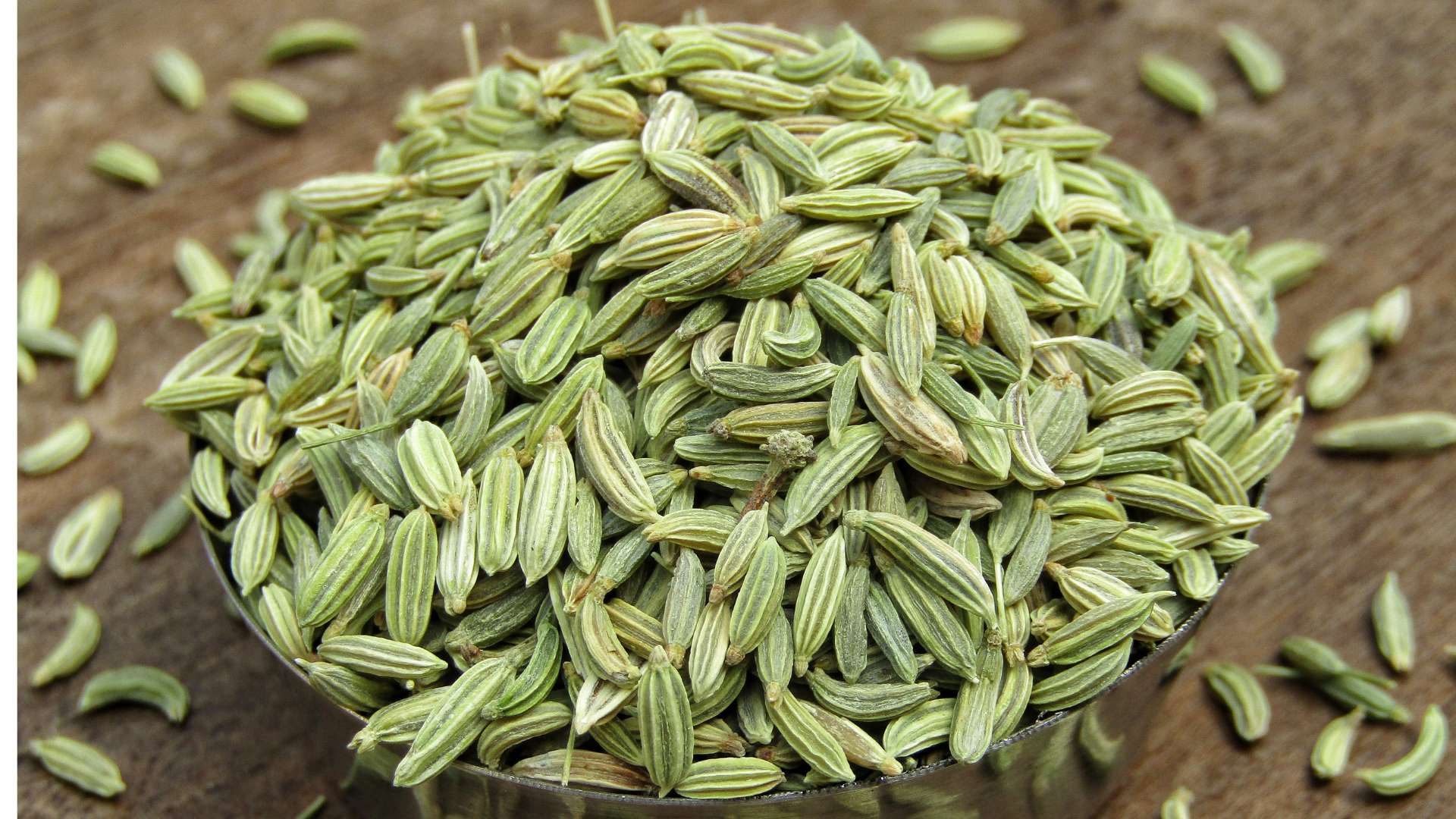 Graines de fenouil dans récipient et sur une table en bois