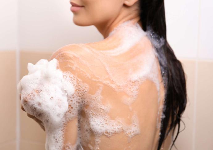 Femme brune cheveux longs sous la douche avec mousse de gel douche sur elle