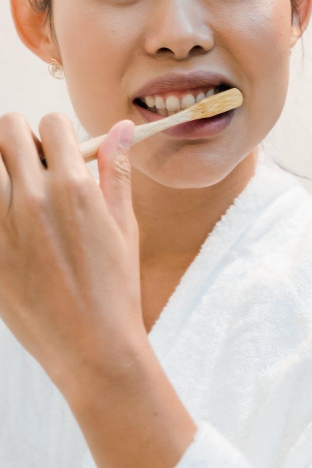 Femme avec peignoir blanc qui se brosse les dents