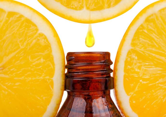 Zitronenscheiben umgeben eine Flasche ätherisches Öl mit Tropfen, der hineinfällt