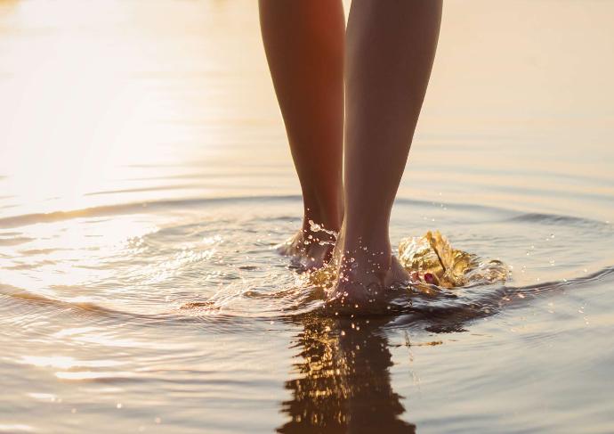 Jambes nues de femme de dos pieds dans l'eau