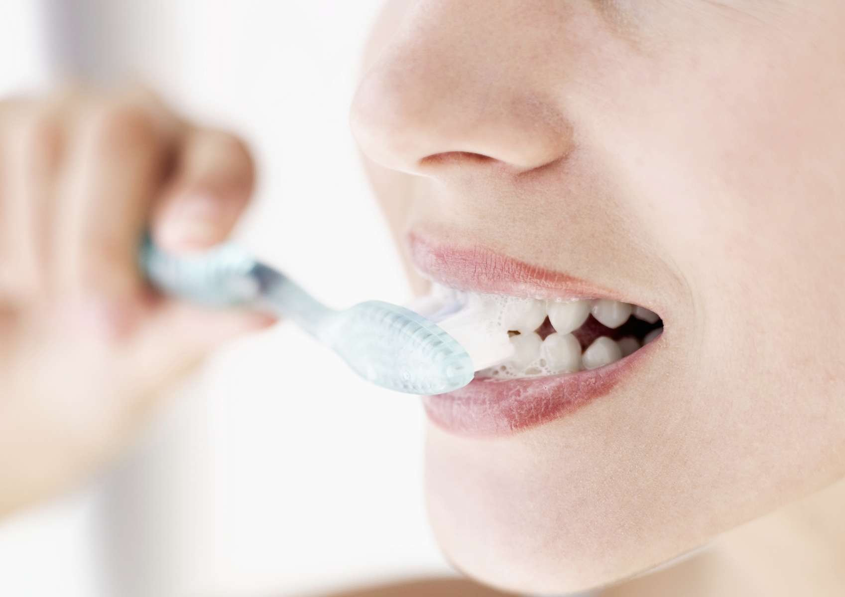 Bouche jeune femme de profil qui se brosse les dents