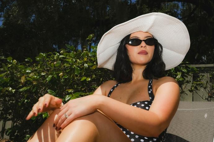 Femme brune maillot de bain à pois, lunettes de soleil et chapeau blanc 