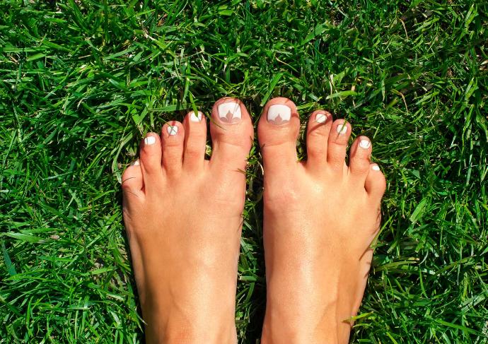 Pieds nus vernis blanc dans l'herbe