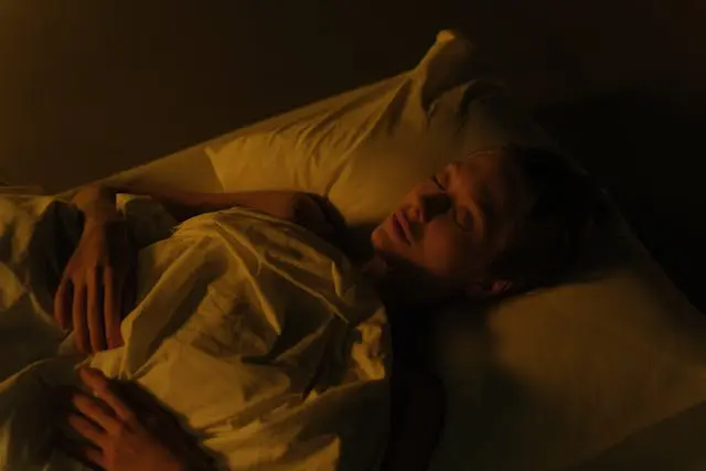 Femme qui dort sur le dos avec oreillers et drap blancs