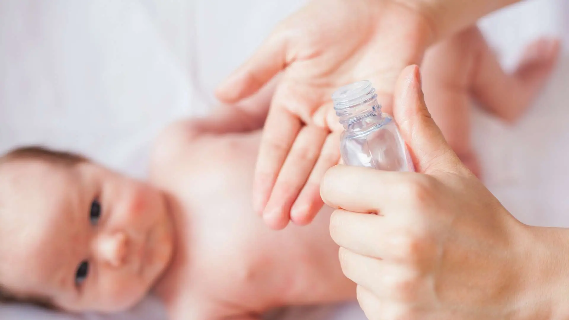 Main de femme tenant un flacon au-dessus d'un bébé en arrière-plan