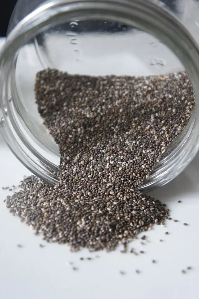 Graines de chia dans un bocal transparent couché et devant le bocal
