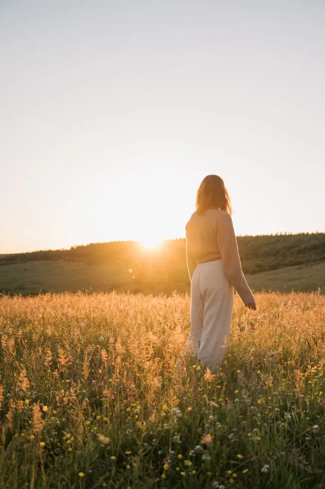 Femme de dos dans un champ face au soleil