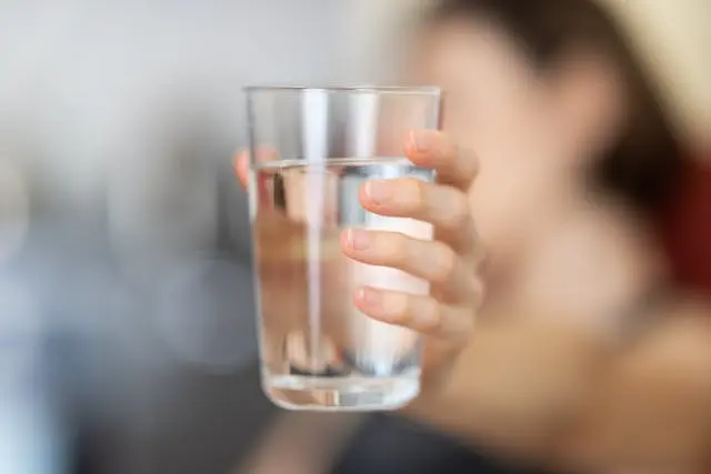 Gros plan verre d'eau tenu par main de femme