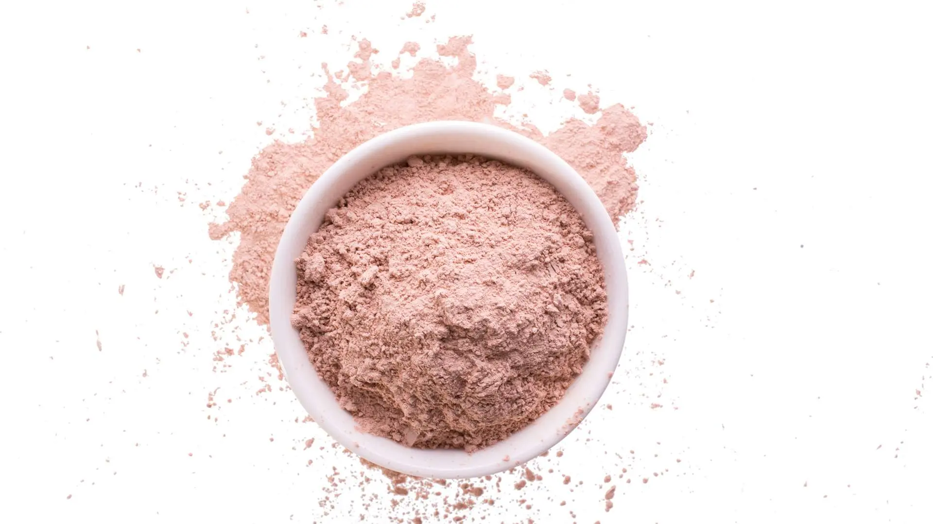 Vue de haut argile rose dans ramequin blanc avec poudre rose autour 