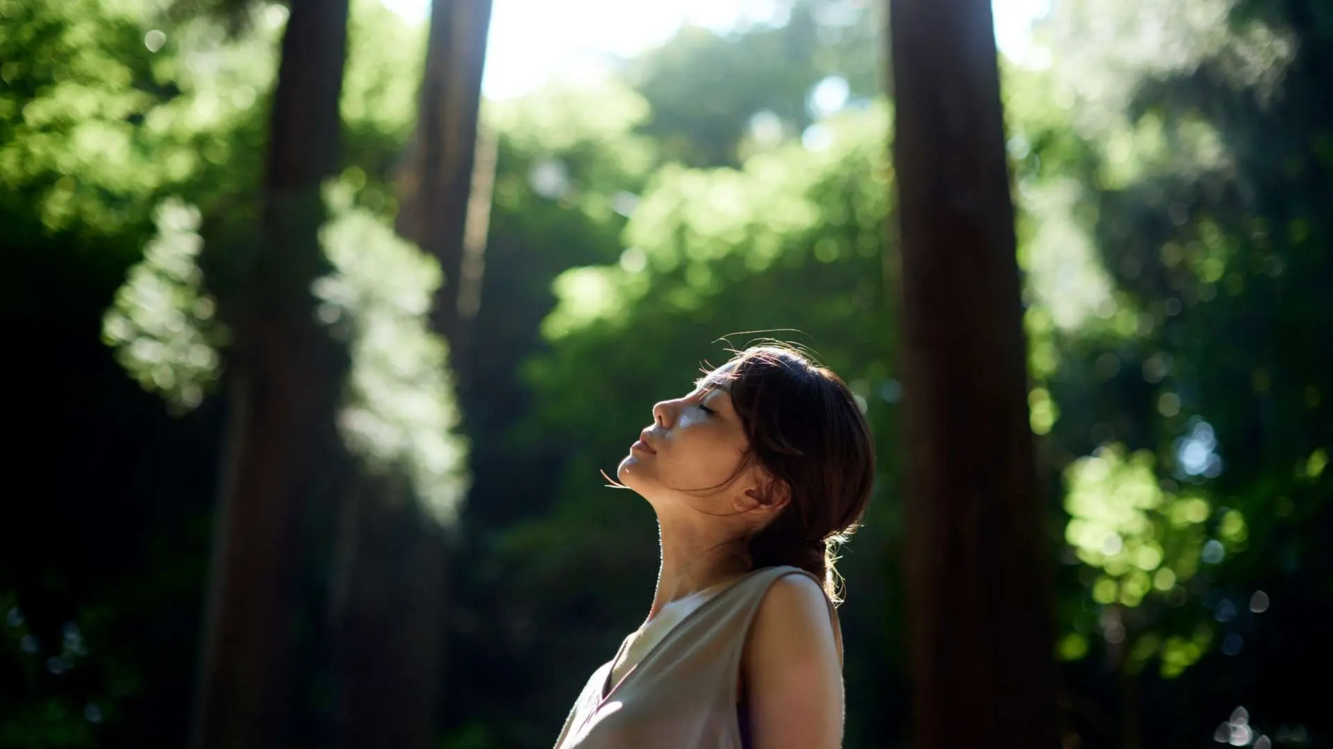 Jeune femme yeux fermés entourée d'arbres