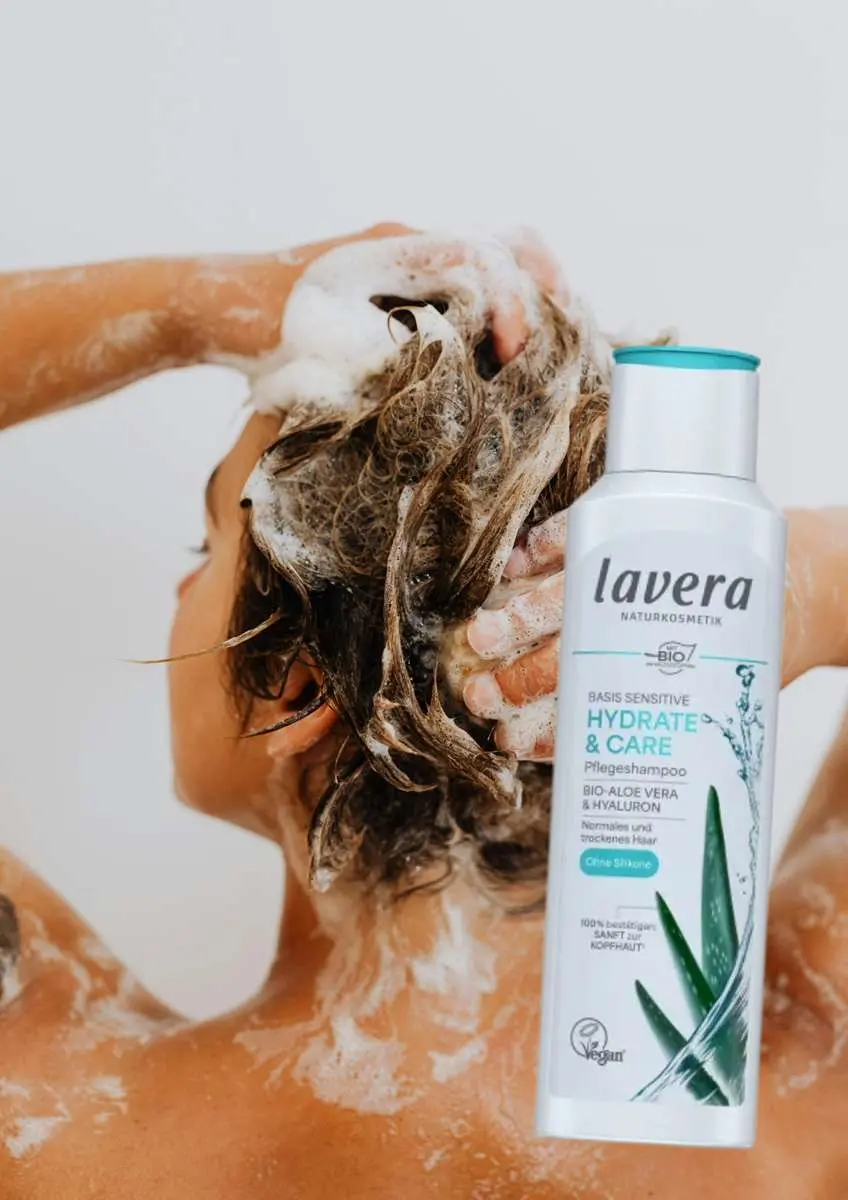 Femme de dos qui se lave les cheveux avec photo de shampoing hydratation & soin Basis Sensitive Lavera