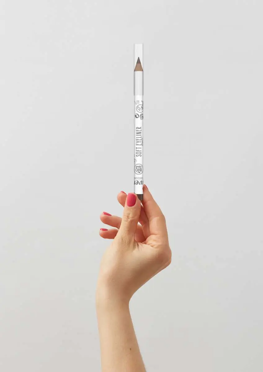 Main de femme avec ongles vernis qui tient un eyeliner doux marron Lavera