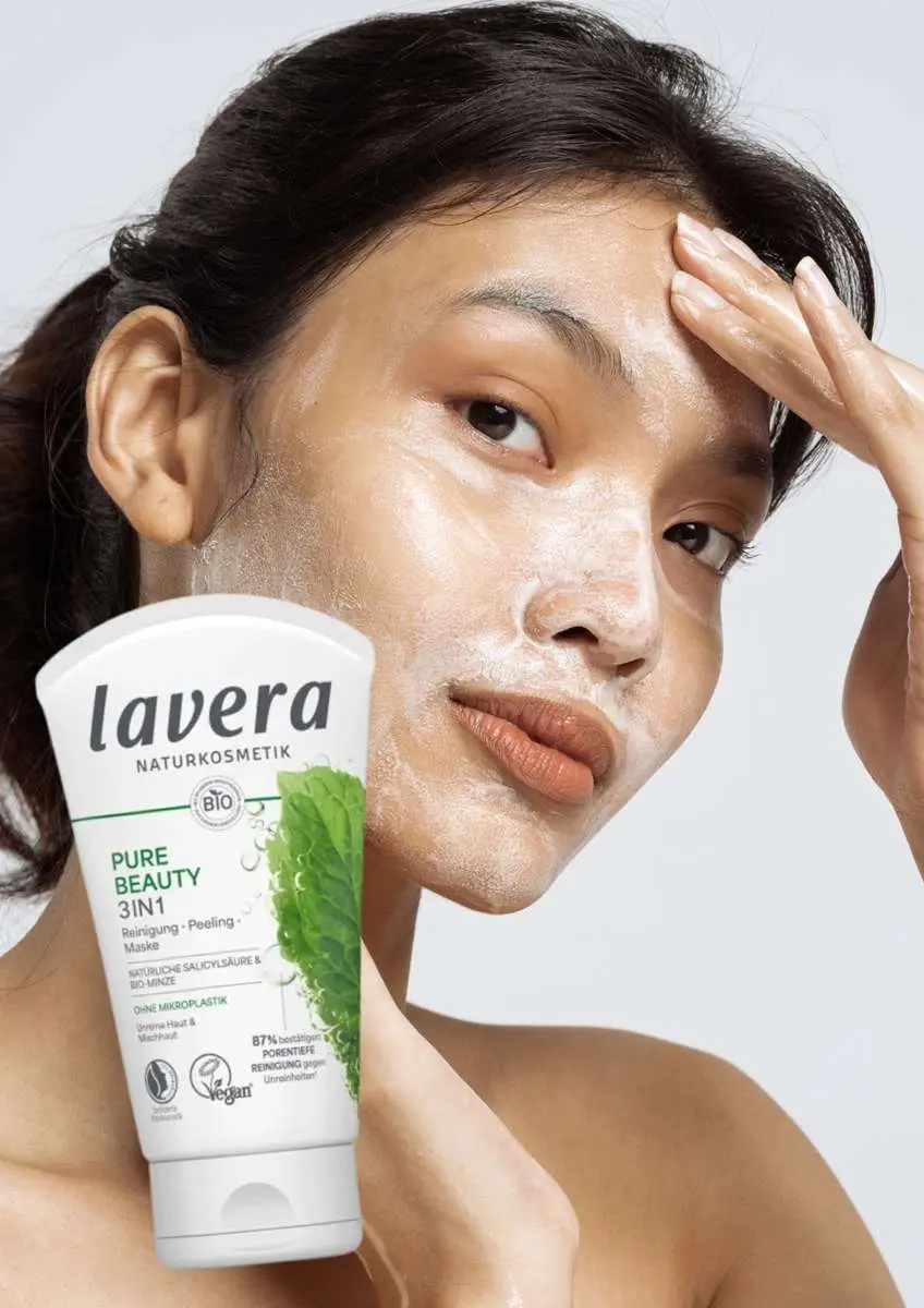 Jeune femme asiatique avec gommage blanc sur le visage et tube  Nettoyant Gommage Masque 3-en-1 Pure Beauty Lavera